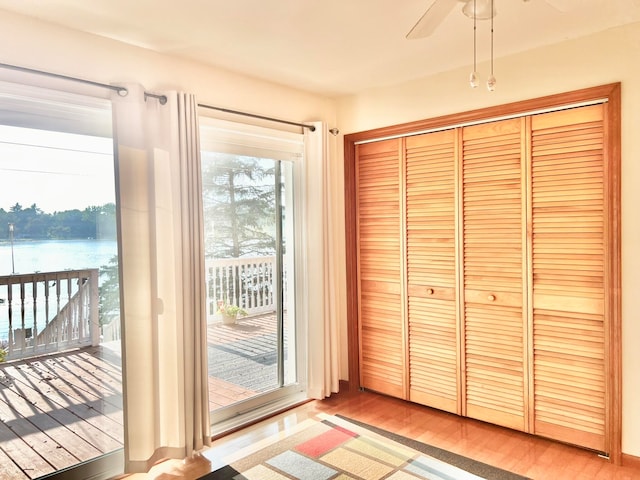 doorway to outside with ceiling fan, light hardwood / wood-style flooring, and a water view