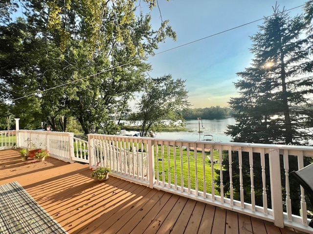 wooden deck with a water view and a lawn