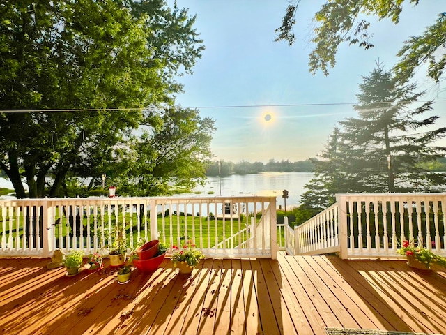 wooden terrace with a water view and a yard