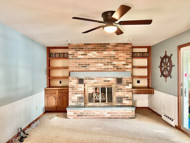 unfurnished living room with a baseboard heating unit, a fireplace, a textured ceiling, ceiling fan, and light colored carpet