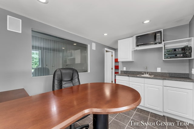 kitchen with white cabinets, dark tile patterned floors, and sink