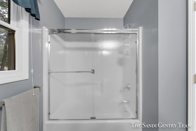 bathroom with enclosed tub / shower combo and a textured ceiling