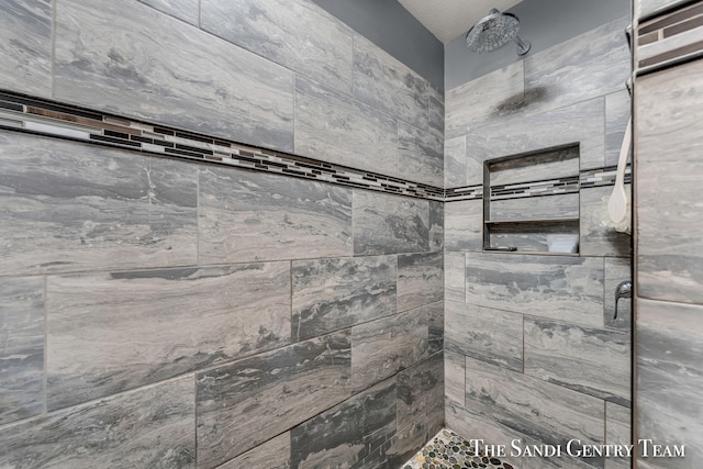 bathroom featuring a tile shower and a textured ceiling