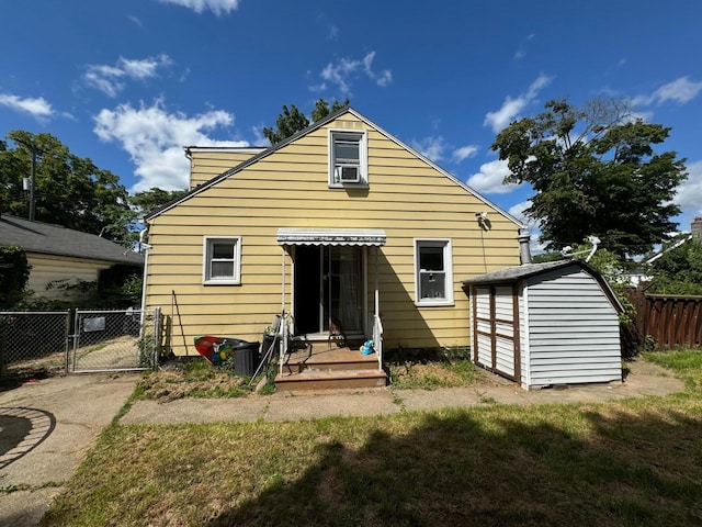 back of property featuring fence, an outdoor structure, a shed, and a gate