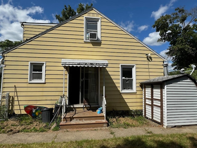 rear view of house featuring a storage unit