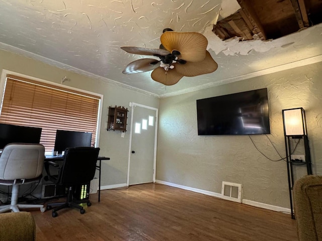 home office with visible vents, baseboards, wood finished floors, and a textured wall