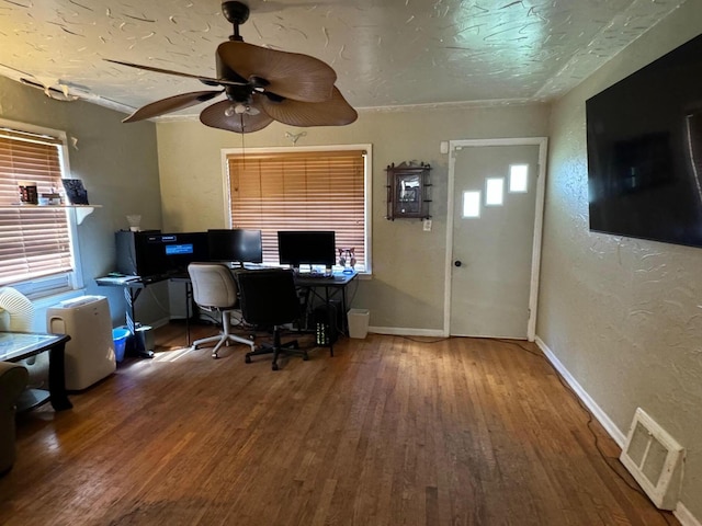 unfurnished office with visible vents, a textured ceiling, wood finished floors, baseboards, and a textured wall