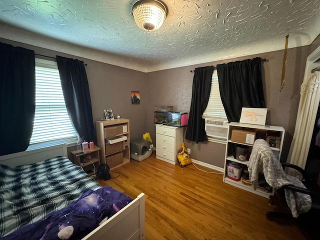 bedroom featuring a textured ceiling, baseboards, and wood finished floors