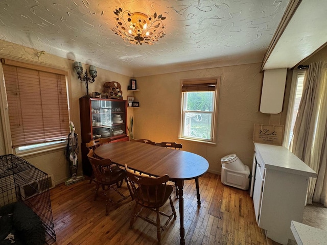 dining space with a textured wall, visible vents, light wood-style floors, and a textured ceiling