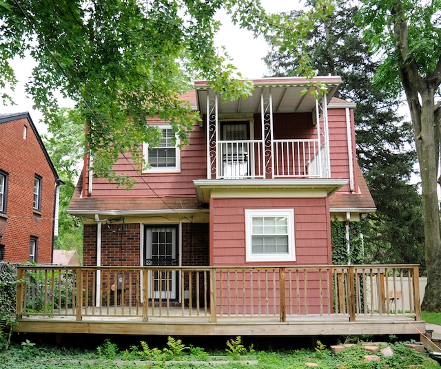 rear view of house featuring a balcony and a deck