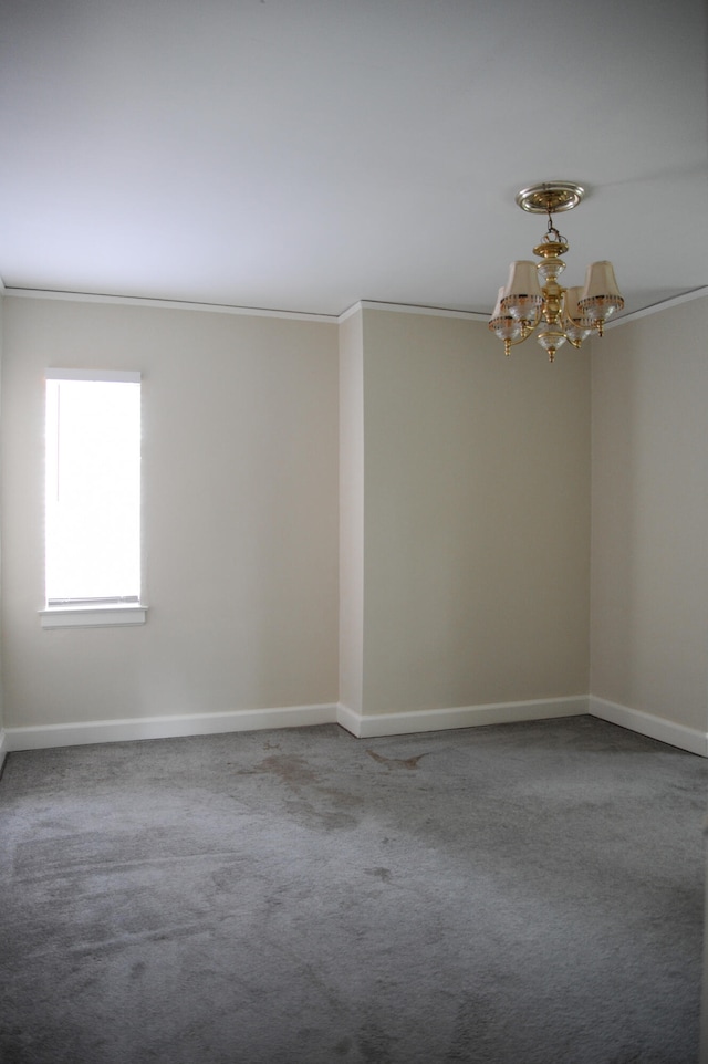 carpeted spare room with ornamental molding and a chandelier