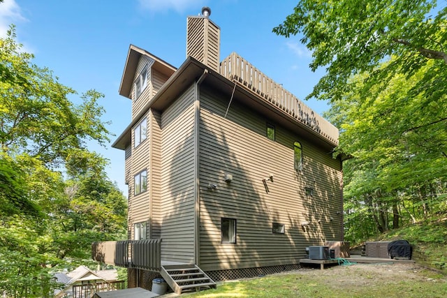 view of property exterior featuring central air condition unit and a chimney