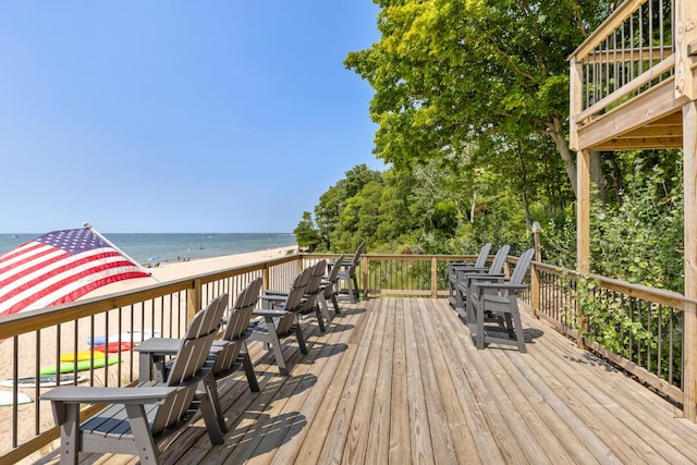 wooden deck featuring a water view and a beach view