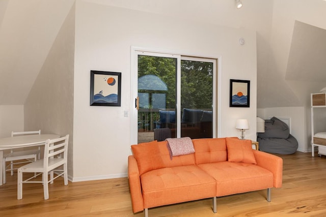 sitting room with lofted ceiling, baseboards, and light wood-type flooring