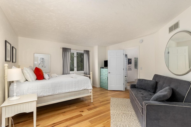 bedroom featuring visible vents, a textured ceiling, and light wood-style floors