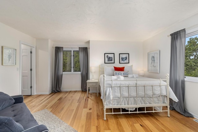 bedroom with wood finished floors, baseboards, and a textured ceiling