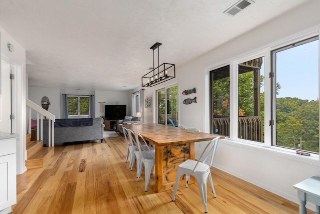 dining space with light wood finished floors, visible vents, stairs, and baseboards