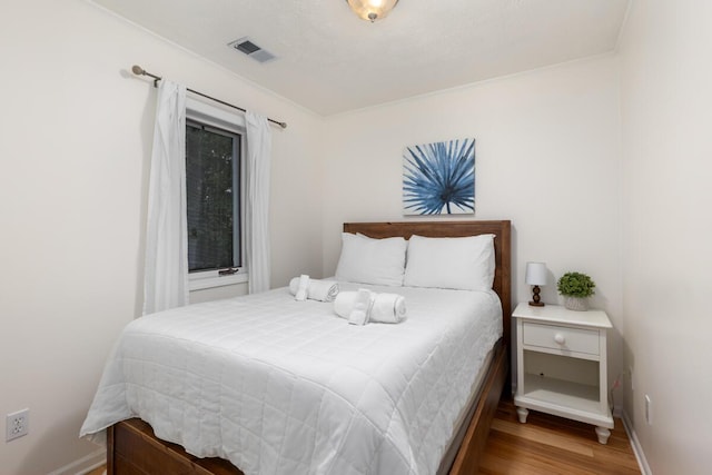 bedroom featuring visible vents, baseboards, and wood finished floors