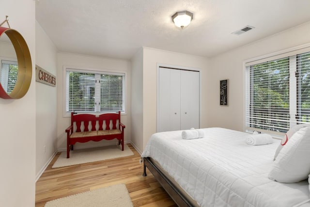 bedroom featuring visible vents, baseboards, a closet, and light wood finished floors