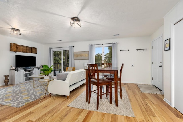 dining room with a wealth of natural light, visible vents, a textured ceiling, and light wood-style flooring