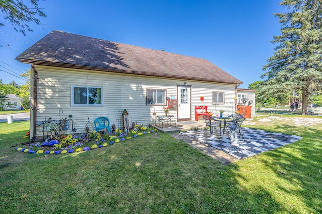 back of house featuring a patio area, a lawn, and roof with shingles