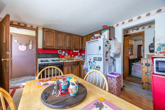 kitchen with a textured ceiling, light countertops, gas range oven, and freestanding refrigerator