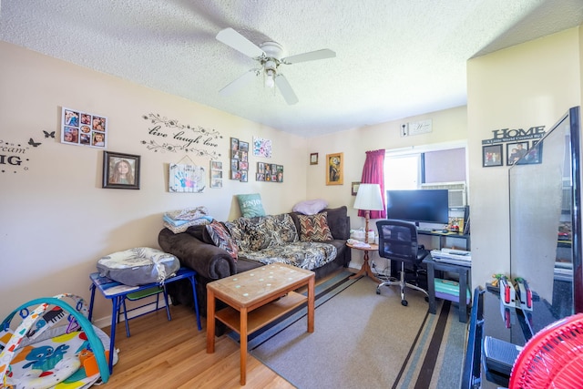 living room with a textured ceiling, a ceiling fan, and wood finished floors