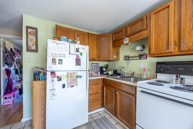 kitchen featuring light countertops, white appliances, a sink, and brown cabinets