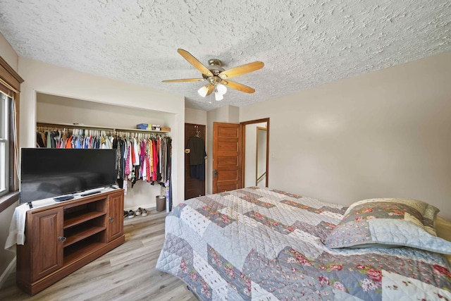 bedroom with ceiling fan, light hardwood / wood-style flooring, a textured ceiling, and a closet