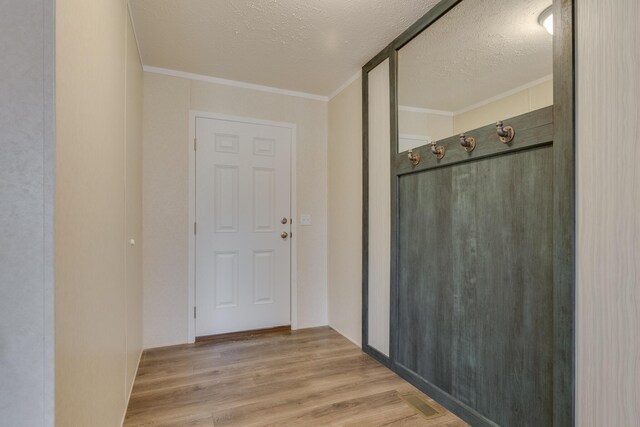 mudroom with a textured ceiling, light hardwood / wood-style floors, and crown molding