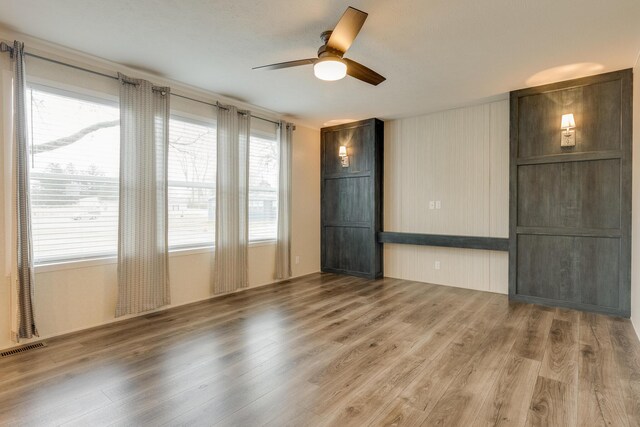 empty room with ceiling fan, hardwood / wood-style flooring, and a healthy amount of sunlight