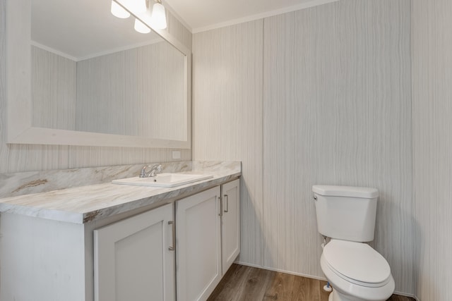 bathroom with toilet, ornamental molding, vanity, and wood-type flooring