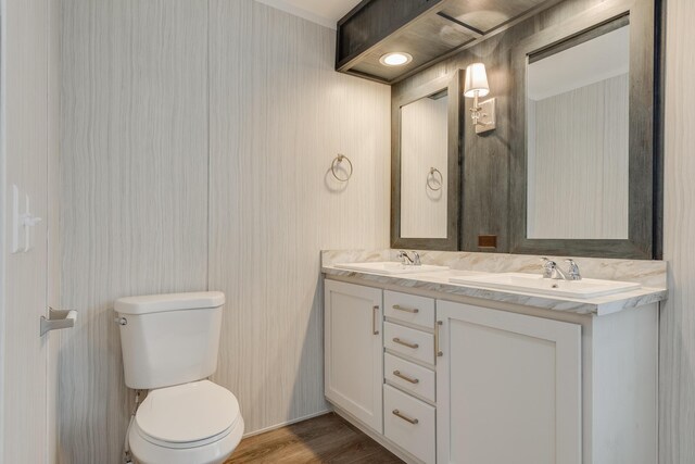 bathroom with double sink vanity, wood-type flooring, and toilet