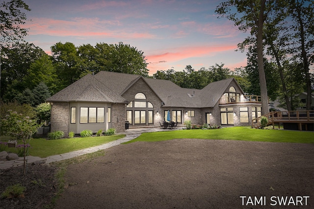 exterior space featuring a front lawn, brick siding, and roof with shingles