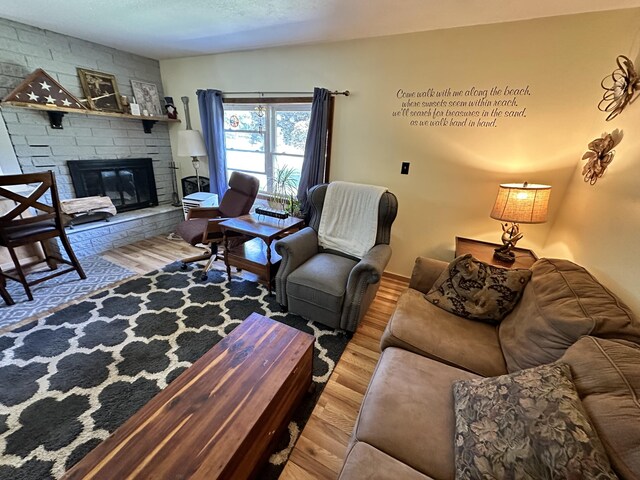 living room featuring a brick fireplace, brick wall, and hardwood / wood-style flooring