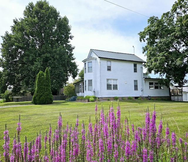 view of home's exterior with metal roof, a lawn, and fence