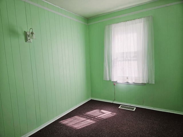 spare room with baseboards, visible vents, and dark colored carpet