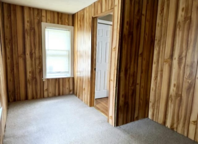 unfurnished room with carpet floors and wood walls