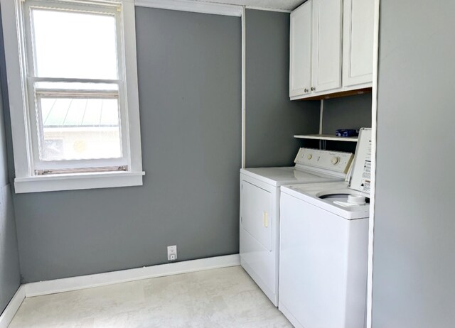 washroom with cabinet space, washer and dryer, and baseboards