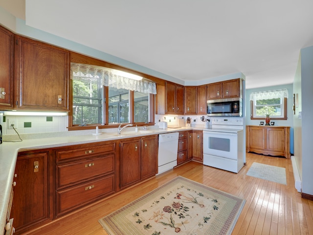 kitchen with backsplash, light wood-type flooring, sink, and white appliances