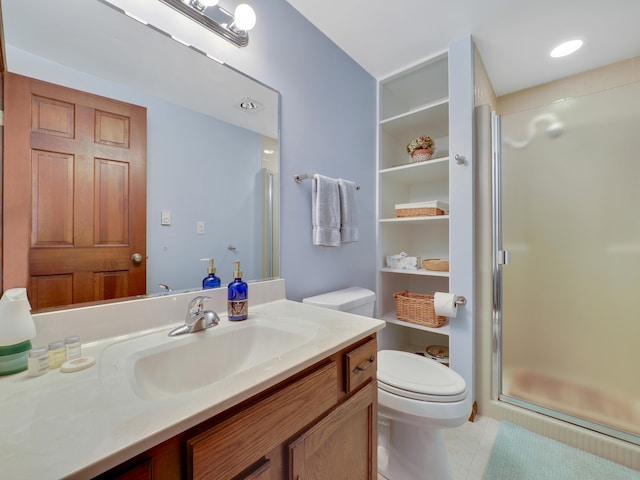 bathroom featuring toilet, tile patterned flooring, a shower with door, and vanity