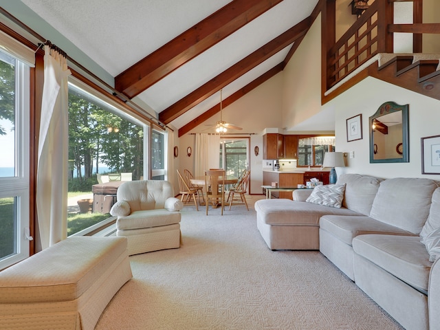 carpeted living room featuring high vaulted ceiling, a healthy amount of sunlight, beam ceiling, and ceiling fan