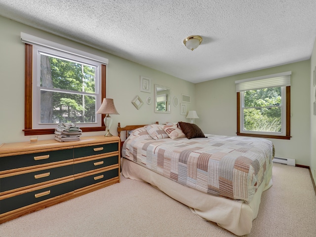 bedroom with a baseboard heating unit, light carpet, multiple windows, and a textured ceiling