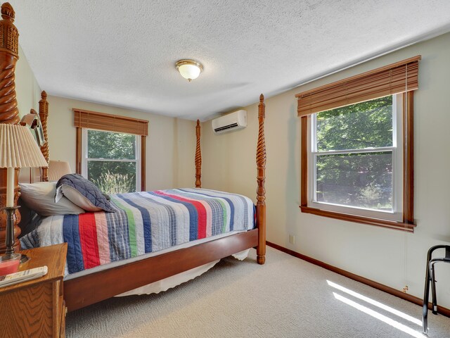 carpeted bedroom featuring multiple windows, an AC wall unit, and a textured ceiling