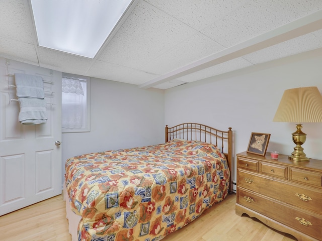 bedroom featuring baseboard heating, a paneled ceiling, and light hardwood / wood-style floors