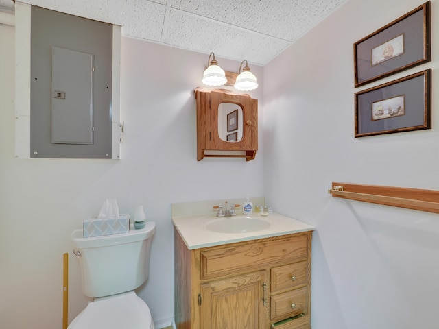 bathroom with a paneled ceiling, toilet, electric panel, and vanity