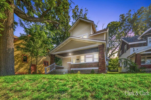 view of front of home featuring covered porch and a yard