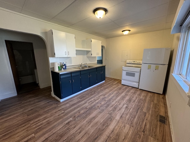 kitchen with white appliances, dark hardwood / wood-style flooring, blue cabinetry, sink, and white cabinets