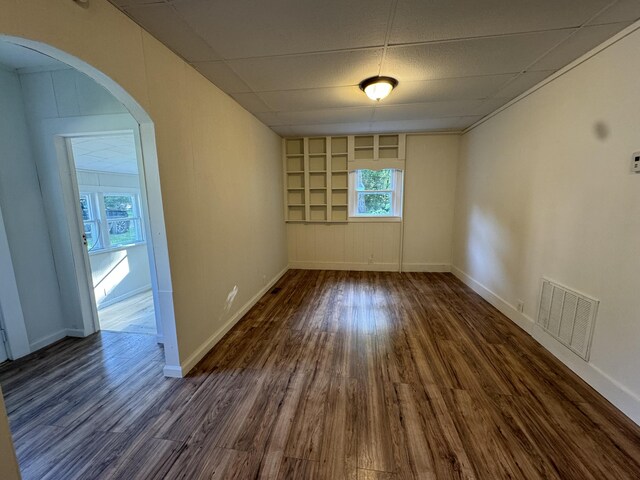 unfurnished room featuring dark hardwood / wood-style flooring and a paneled ceiling