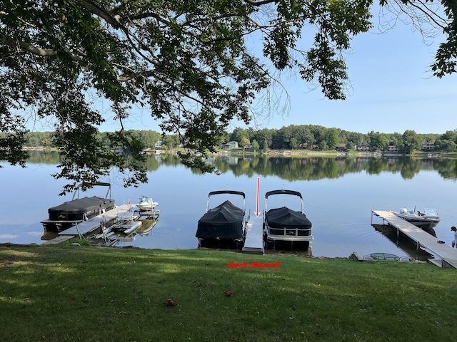 dock area featuring a lawn and a water view